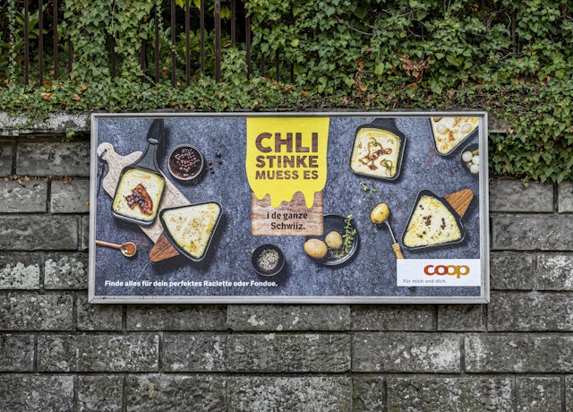 Ein Plakat an einer Steinmauer wirbt für Raclette.