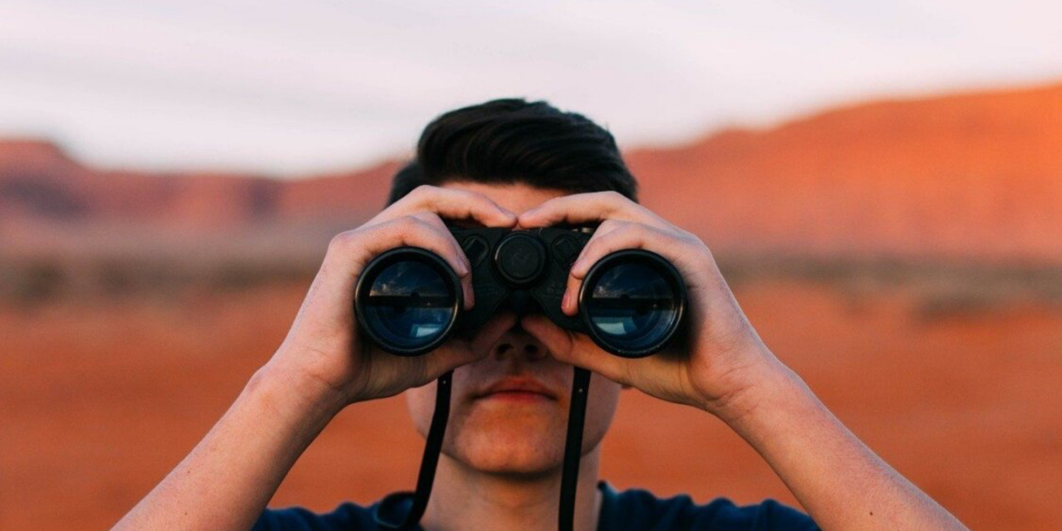 Home avec des jumelles dans un desert