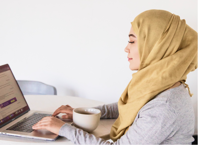 Woman working on a computer with a cup of coffee