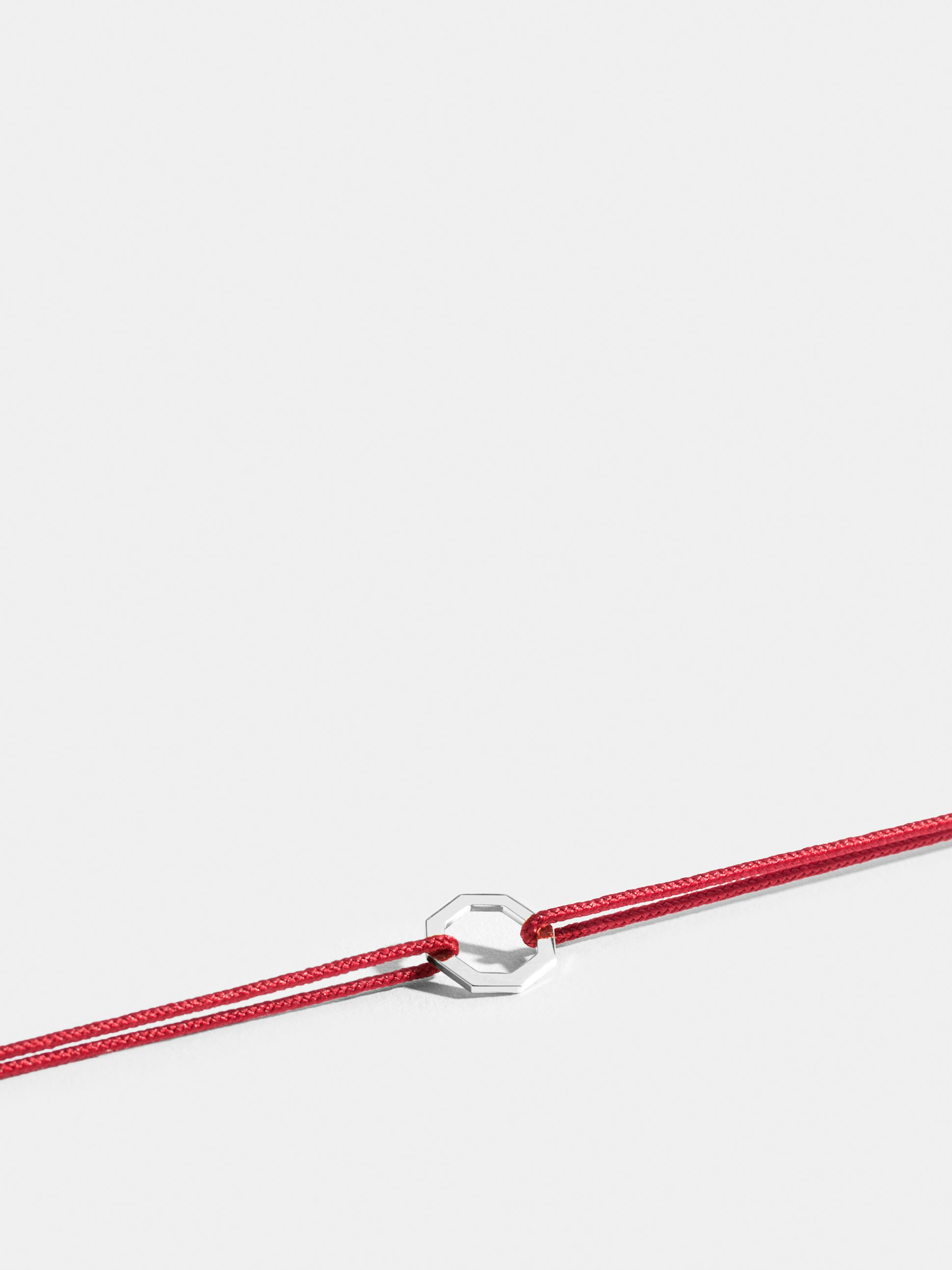 Octogone motif in 18k Fairmined ethical white gold, on a poppy red cord. 