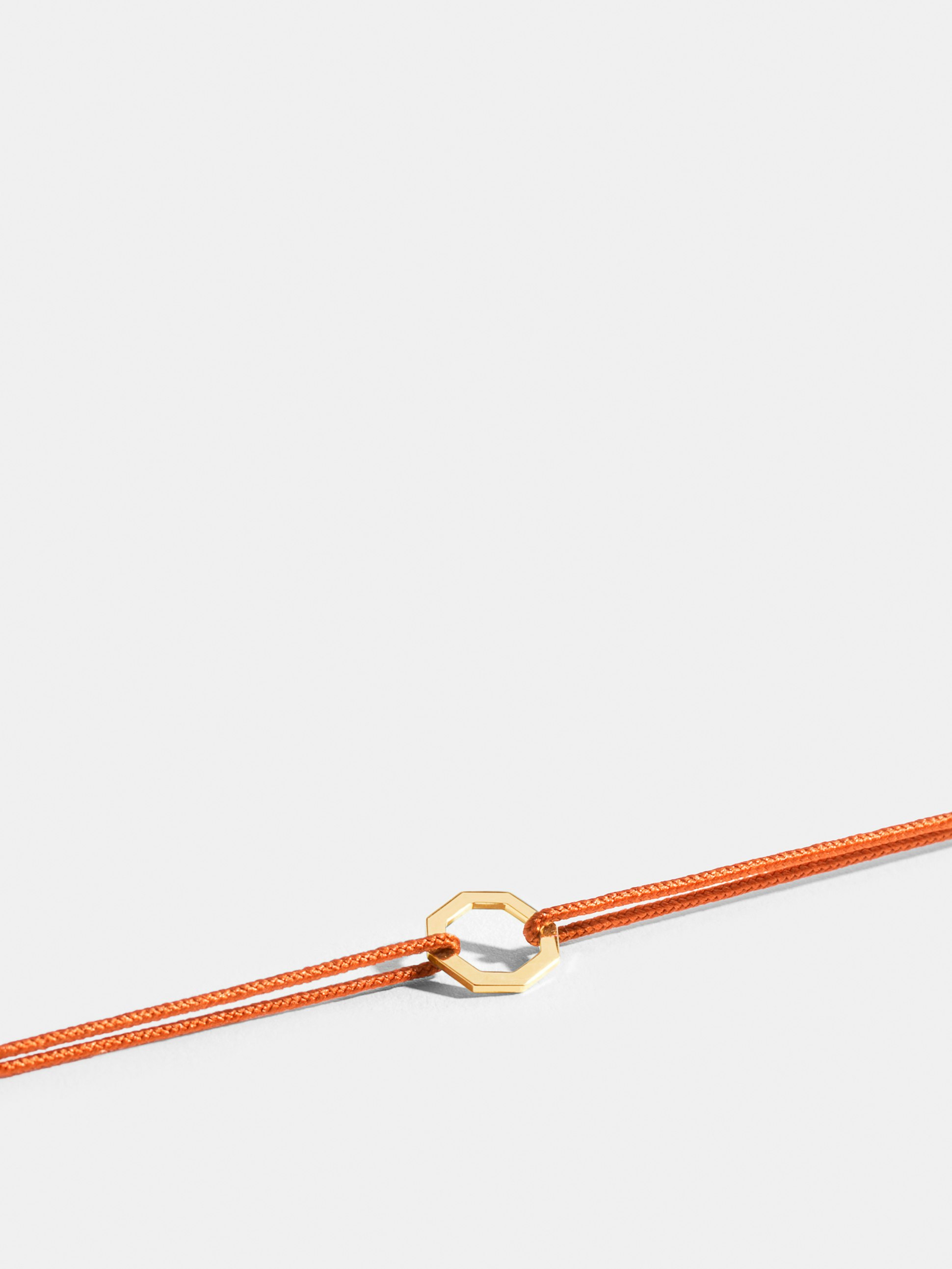 Octogone motif in 18k Fairmined ethical yellow gold, on a bright orange cord. 