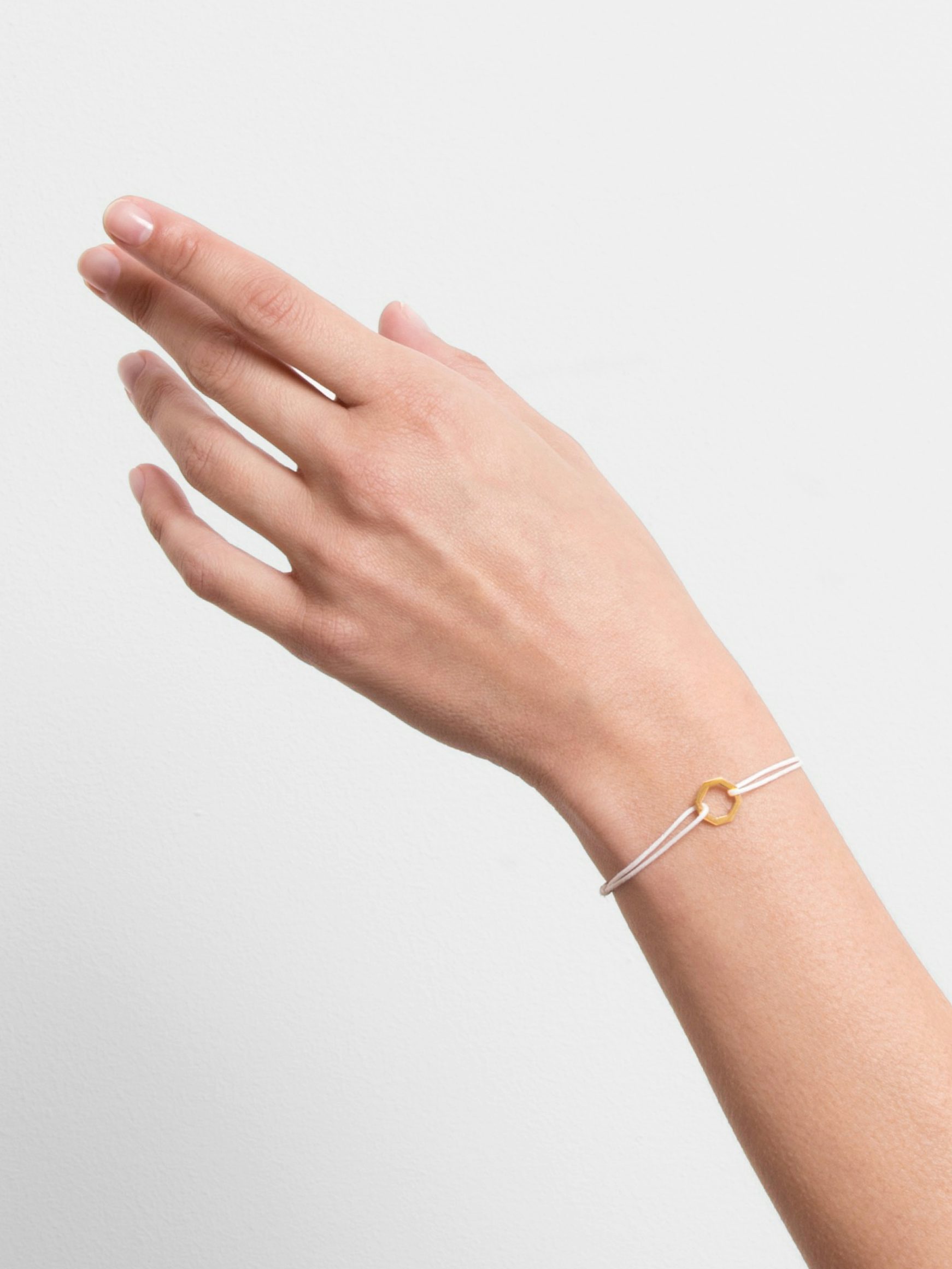 Octogone motif in 18k Fairmined ethical yellow gold, on a bright orange cord.