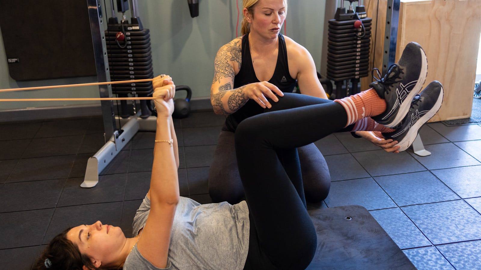 PT talking to a client using a floor mat and bands in Jess-fit studio