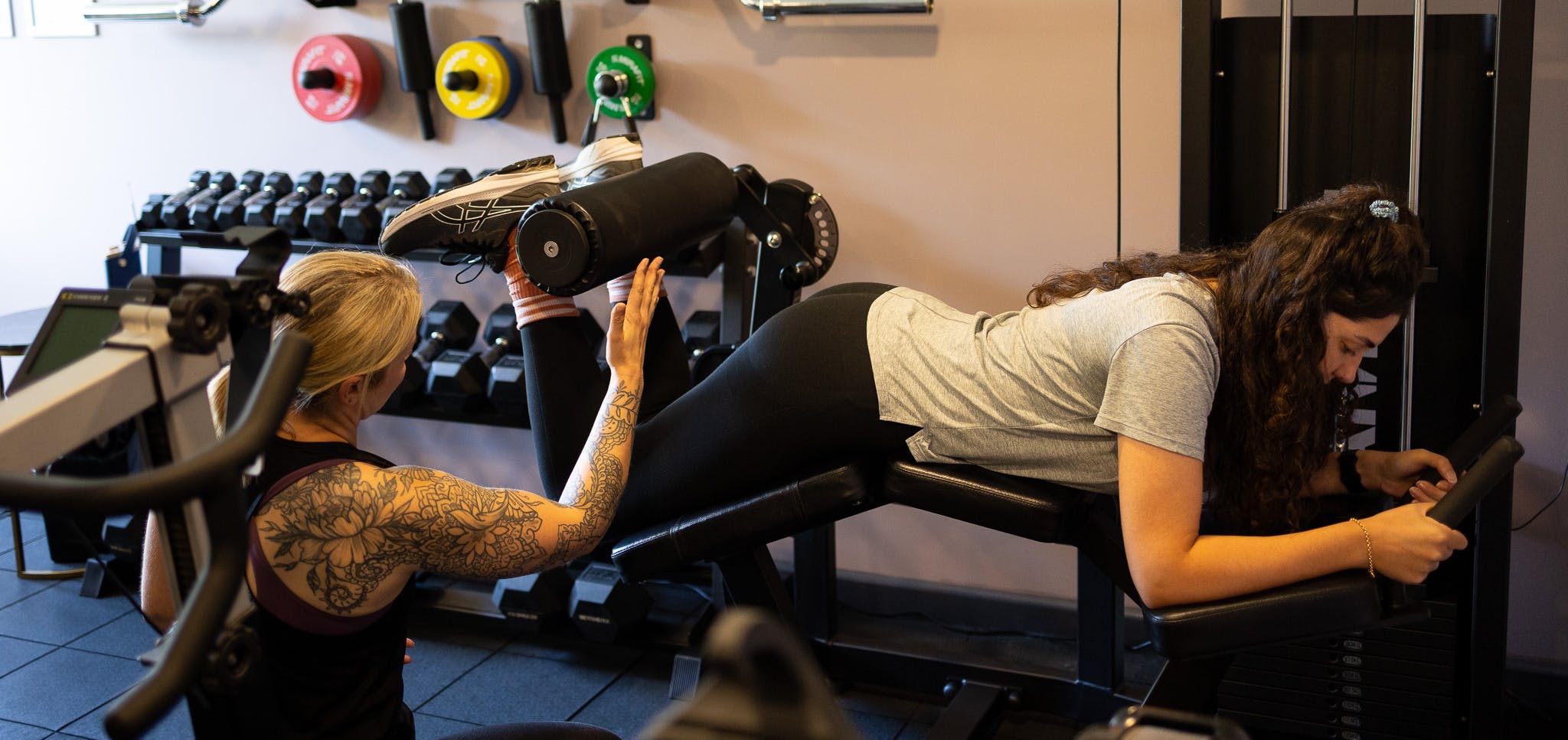 PT talking to a client on Leg curl machine in Jess-fit studio
