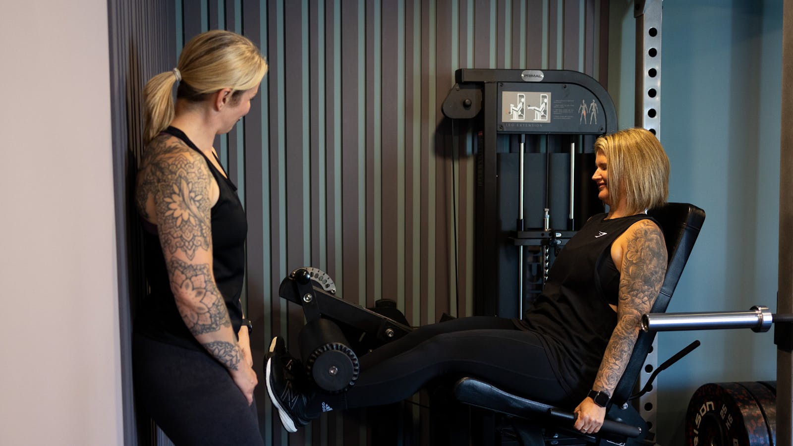 PT talking to a client on leg exercise machine in Jess-fit studio