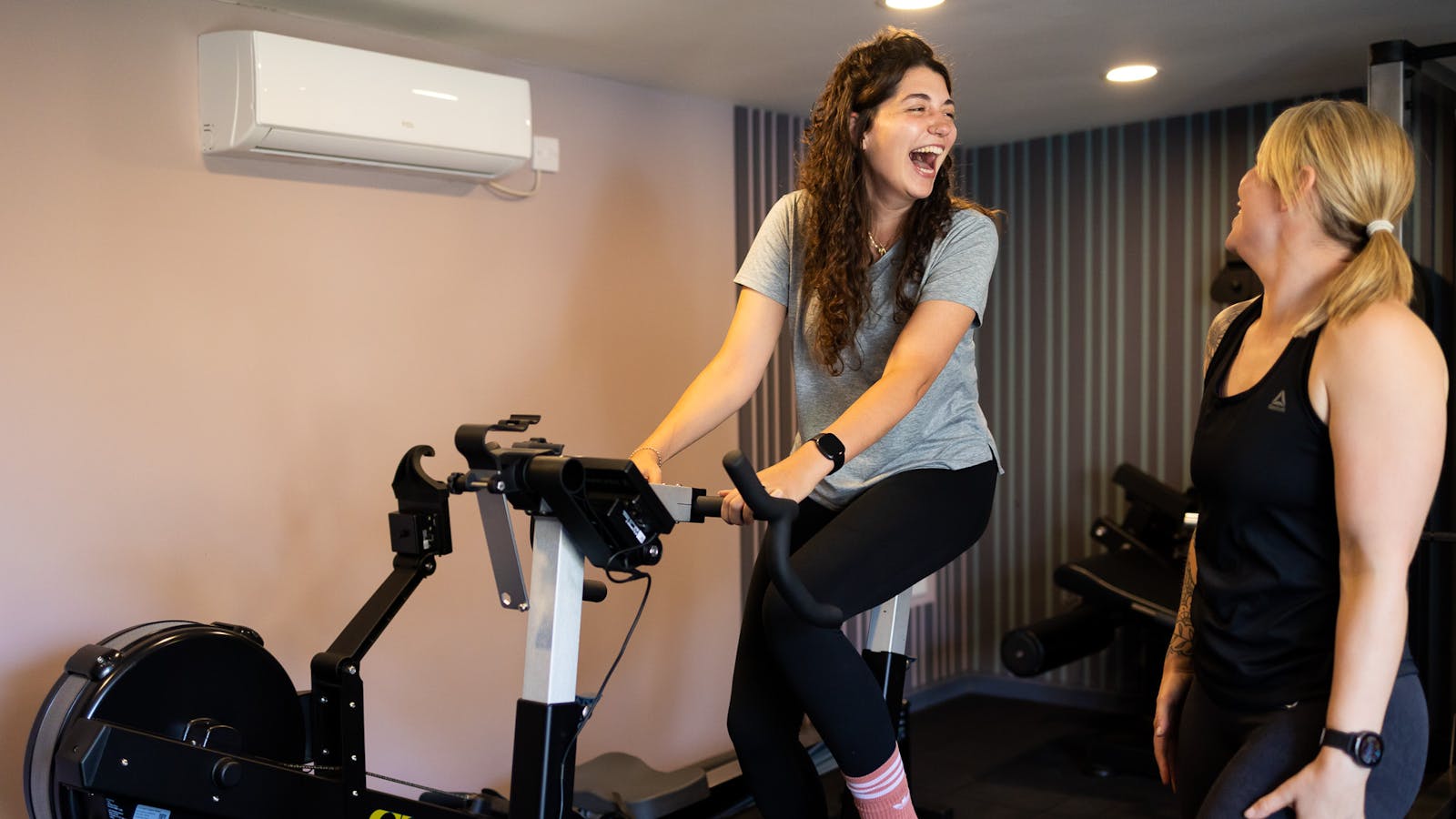 PT talking to client on exercise bike in Jess-fit studio