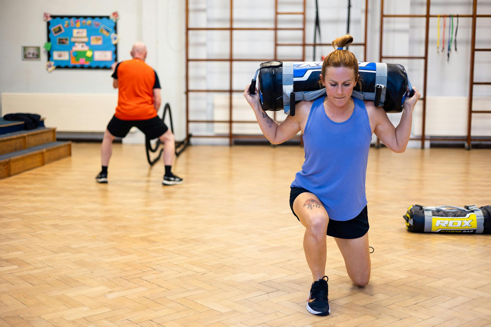 client working with weighted bag at Jess-Fit circuit training class