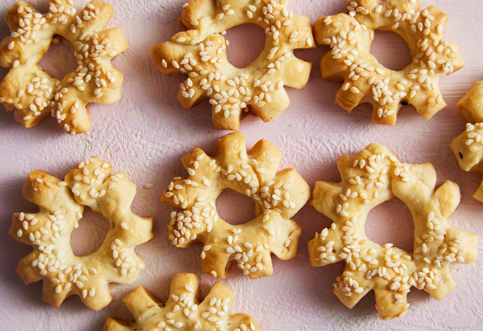 Ka'ak sprinkled with sesame seeds atop pink surface.