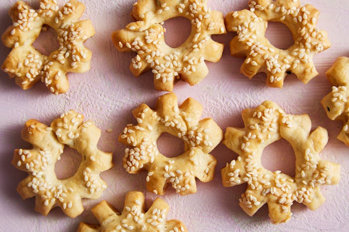 Ka'ak sprinkled with sesame seeds atop pink surface.