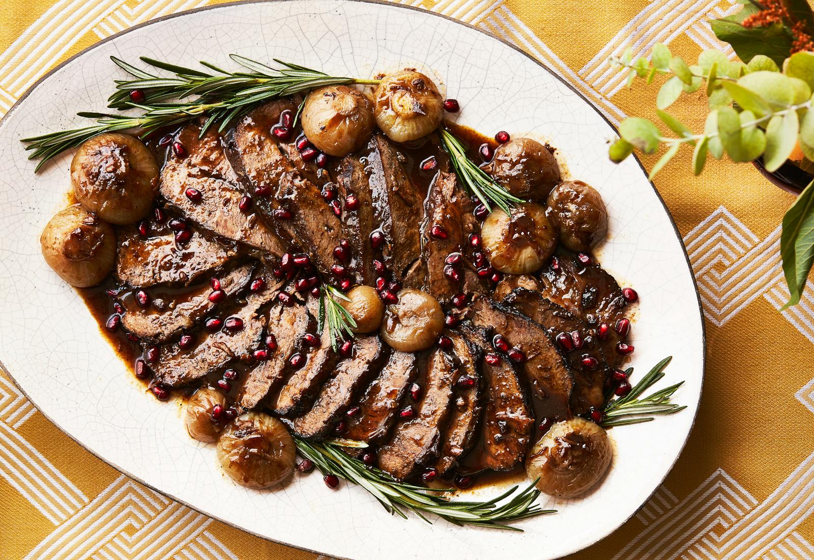 Sliced chuck roast on serving platter, garnished with rosemary.