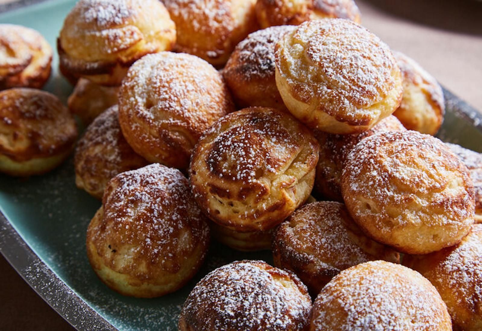 Doughnuts sprinkled with powdered sugar on blue plate.