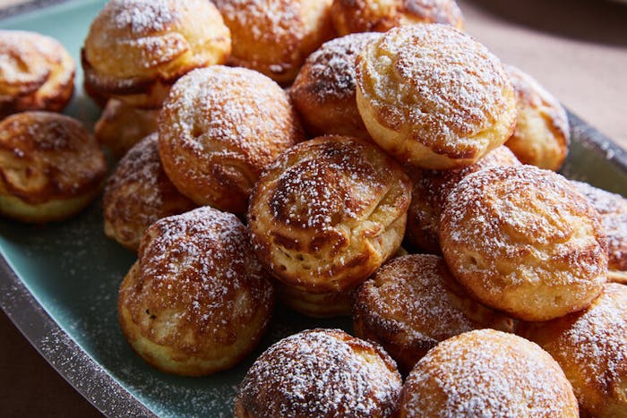 Doughnuts sprinkled with powdered sugar on blue plate.