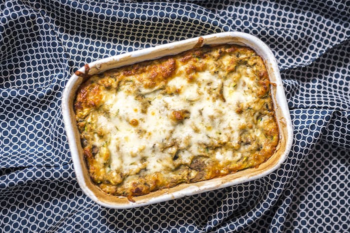 Roasted eggplant and kashkaval pie in white baking dish atop blue and white tablecloth.