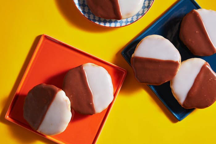 Black and white cookies on various colorful plates atop yellow surface.
