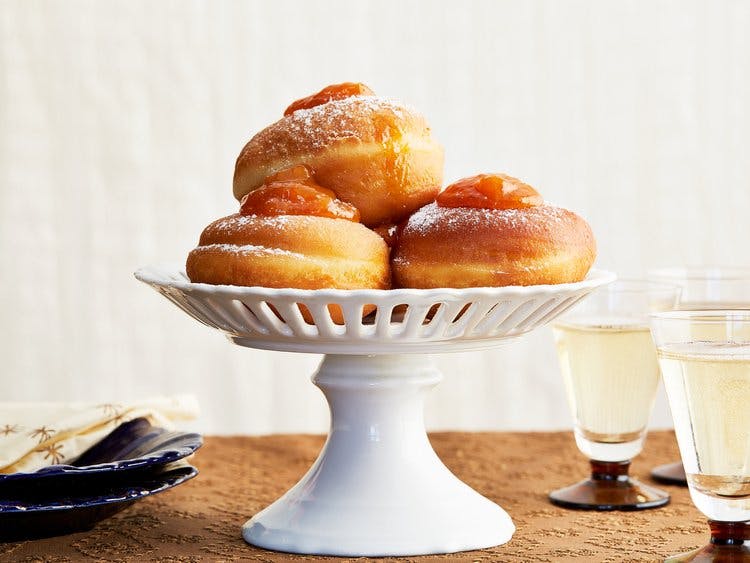 Fank or jam filled doughnuts on a white ceramic cake stand.