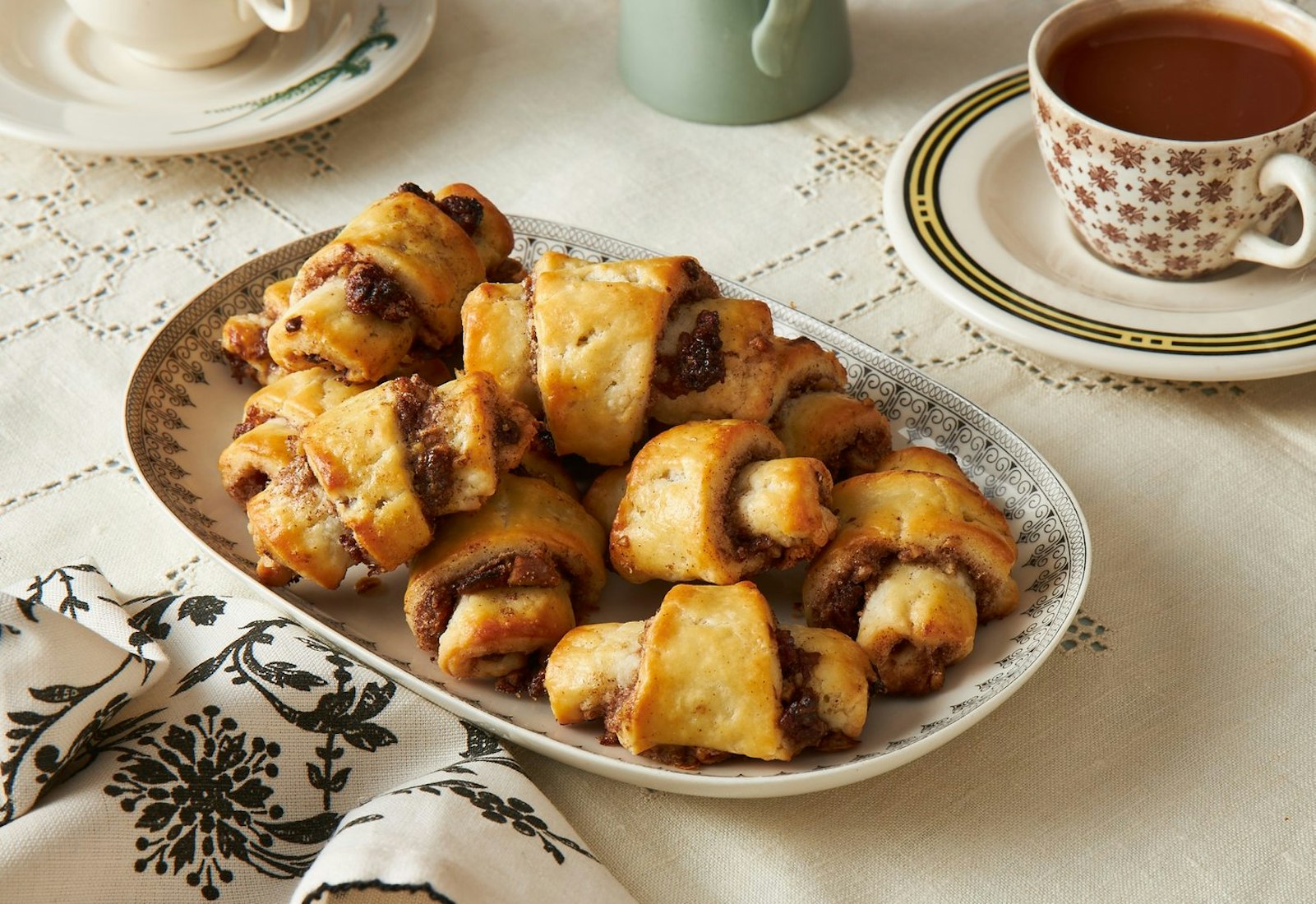 Rugelach cookies with coffee and patterned napkin.