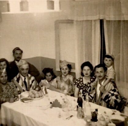 A holiday dinner in Shapira, Tel Aviv in Hananya’s home in the 1950’s. Hananya is on the left side earring a Joma, a Bukharian silk coat that is customary on the holiday. His children and grandchildren sit around him.