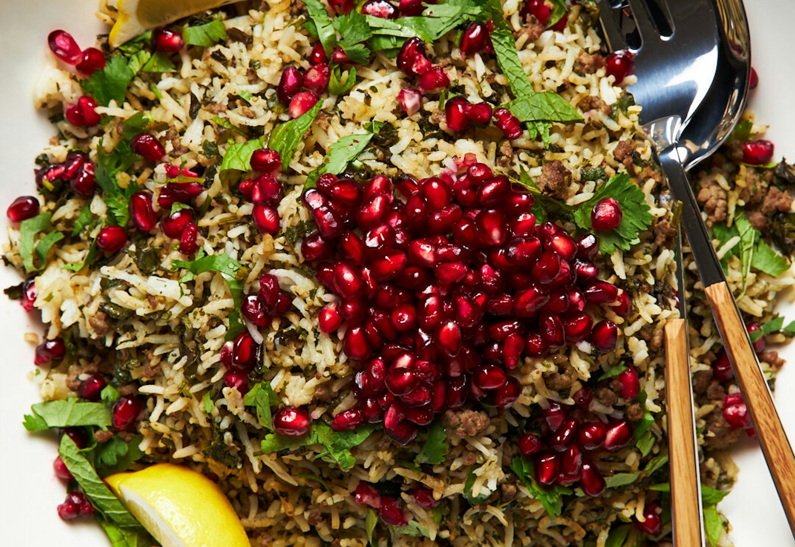 Oshi bakhsh garnished with pomegranate kernels and mint with lemon wedges.