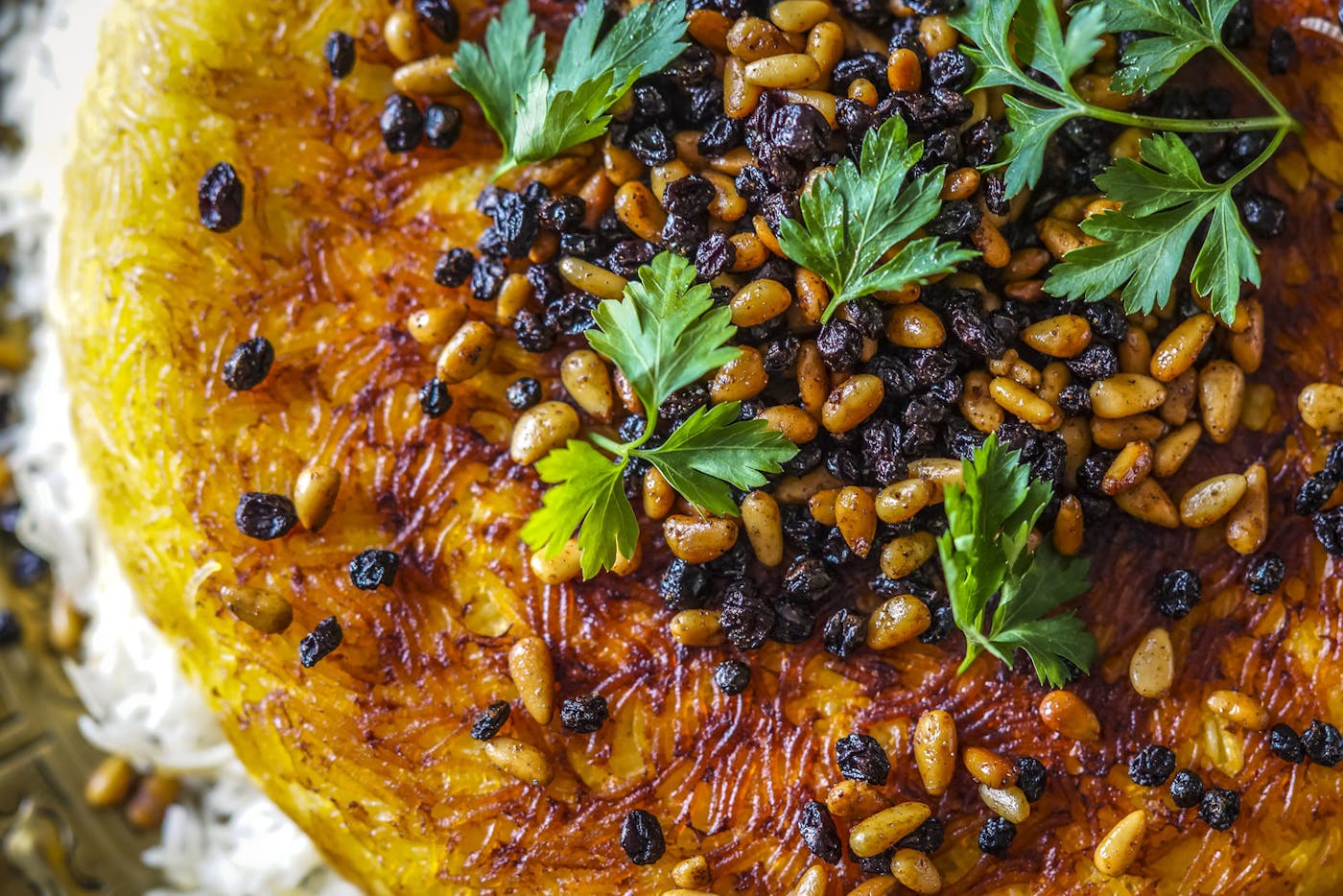 Polo with tahdig garnished with pine nuts, currants and parsley.