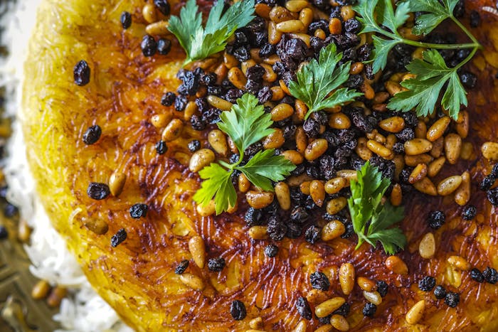 Polo with tahdig garnished with pine nuts, currants and parsley.