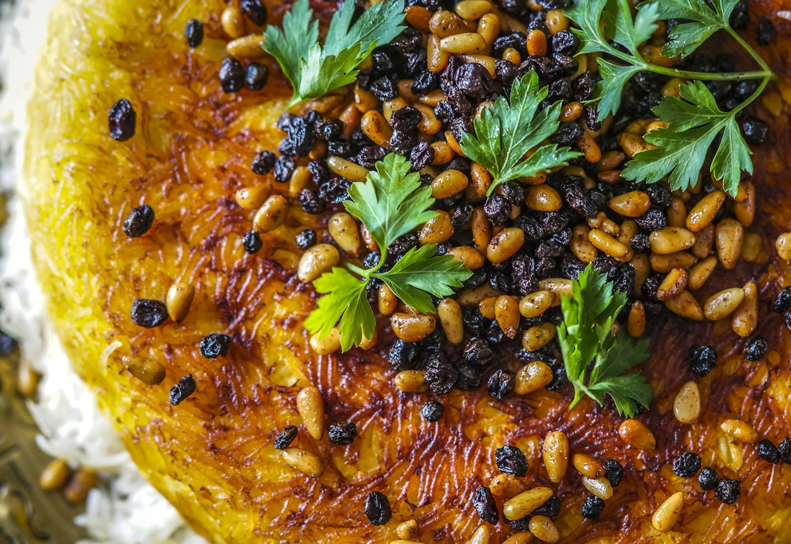 Polo with tahdig garnished with pine nuts, currants and parsley.