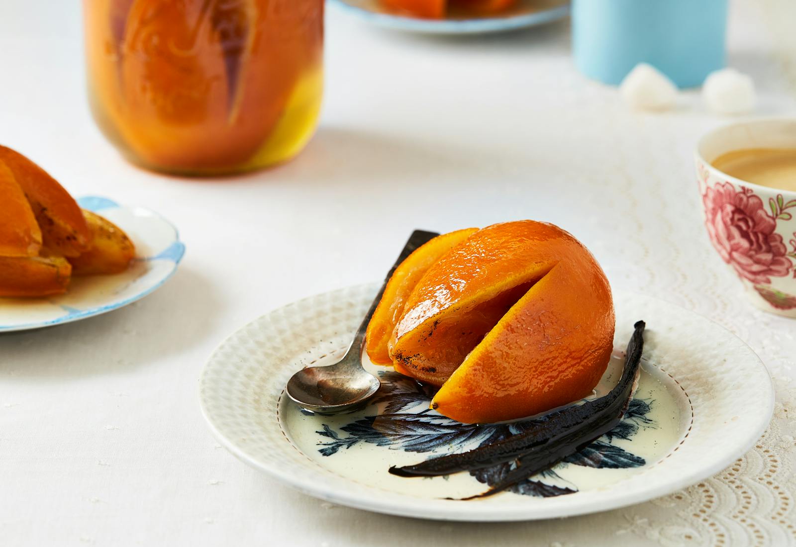 Candied orange on small white plate alongside whole vanilla bean.
