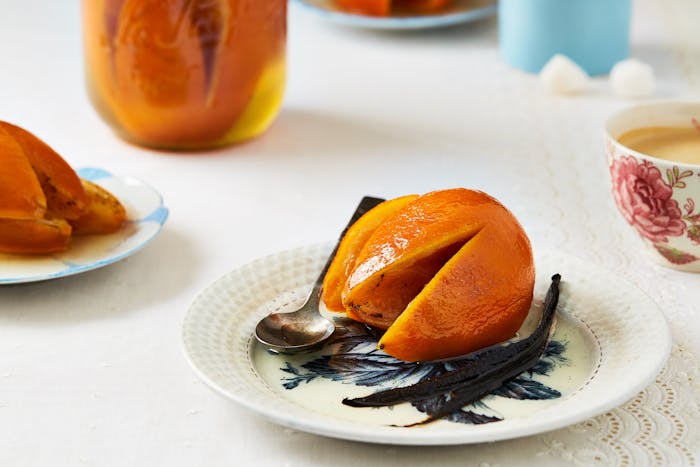 Candied orange on small white plate alongside whole vanilla bean.