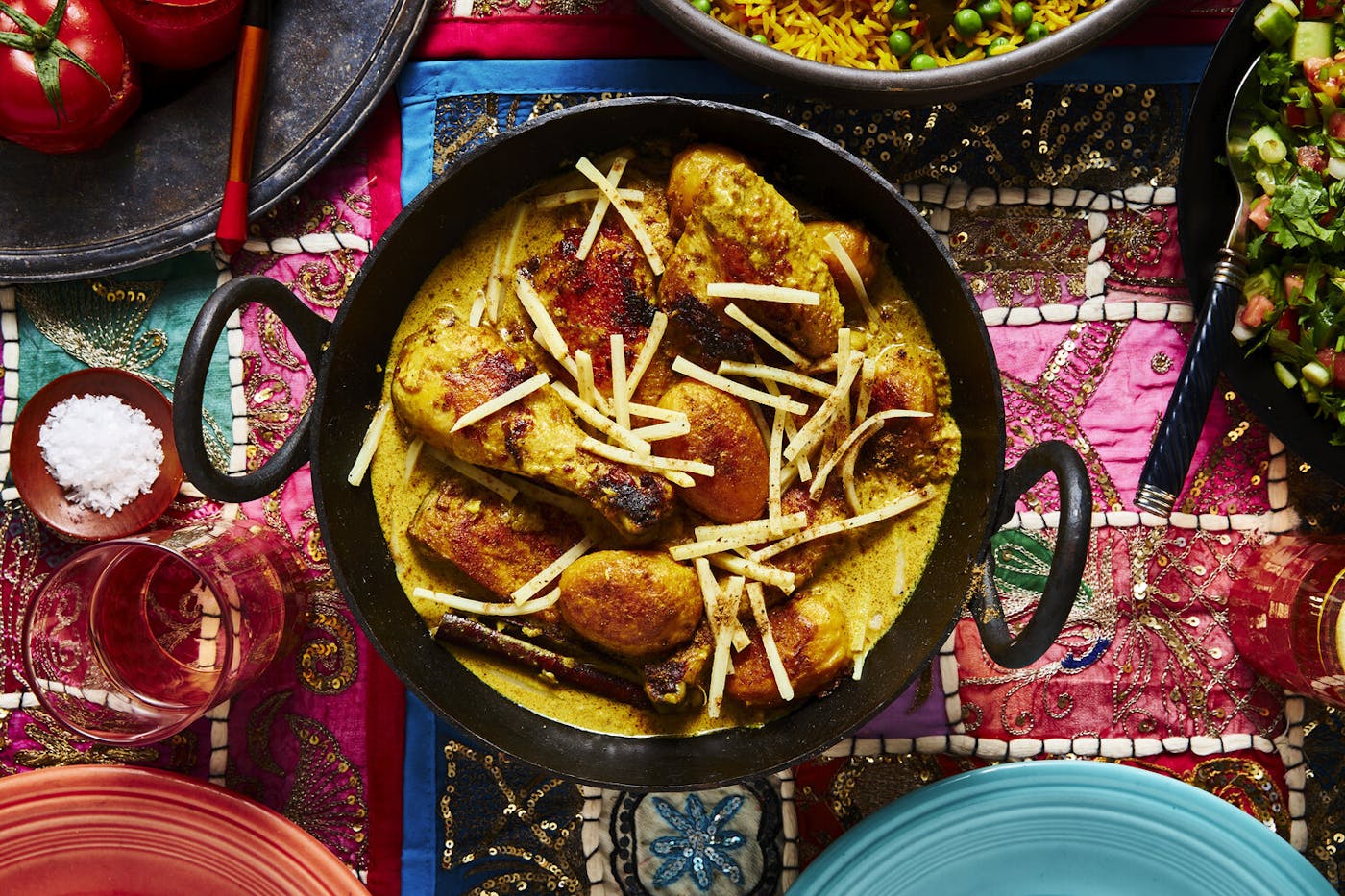 Spayty in cast iron pot alongside mahasha and rice pilau atop vibrant tablecloth.