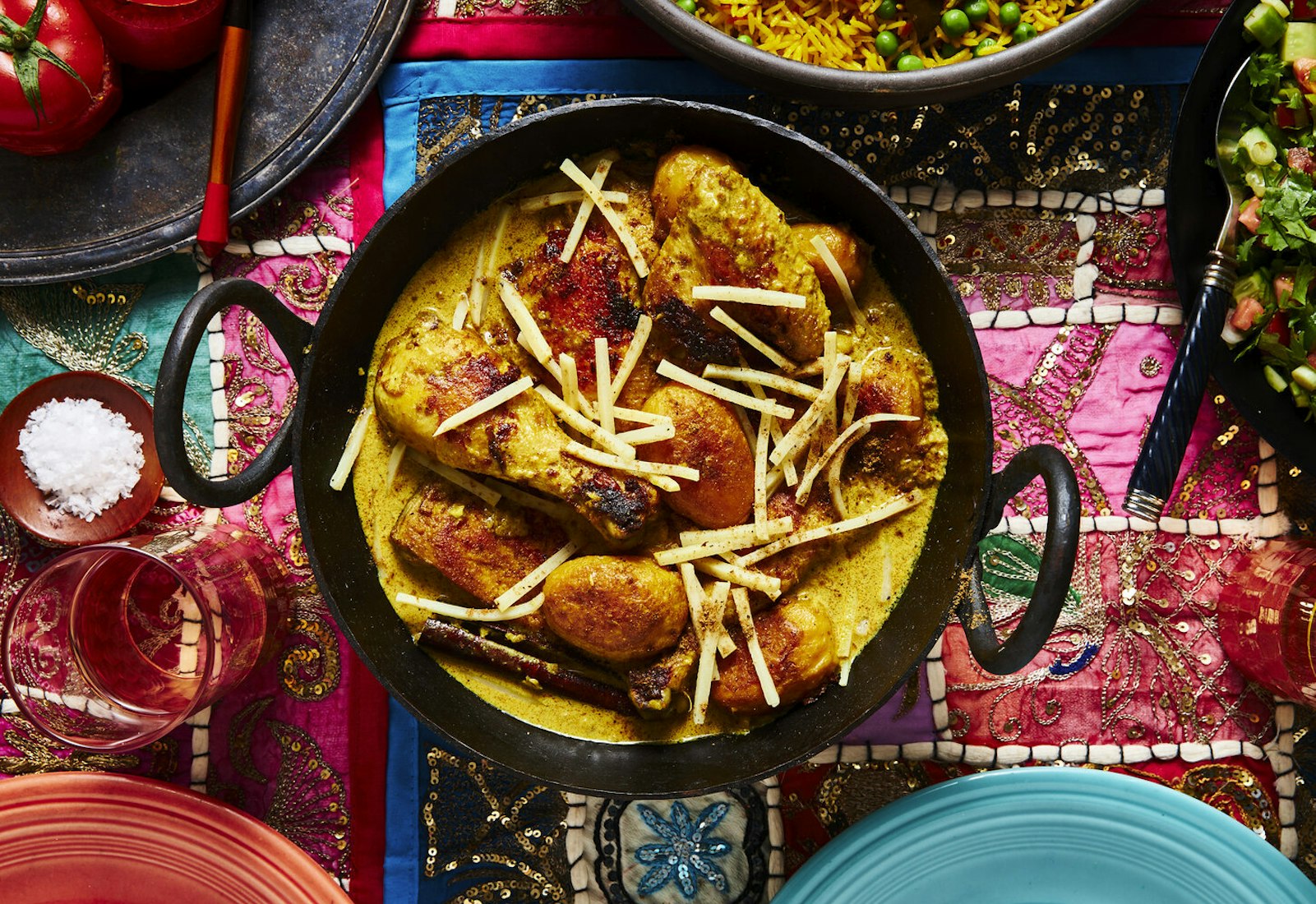 Spayty in cast iron pot alongside mahasha and rice pilau atop vibrant tablecloth.