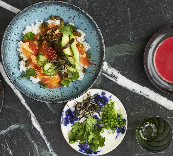 Serving of lox bowl alongside fresh garnishes.