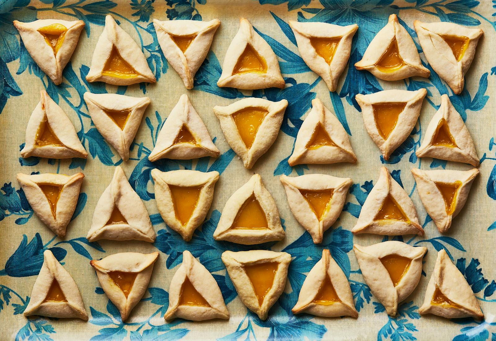 Lemon curd-filled hamantaschens on blue floral dish.