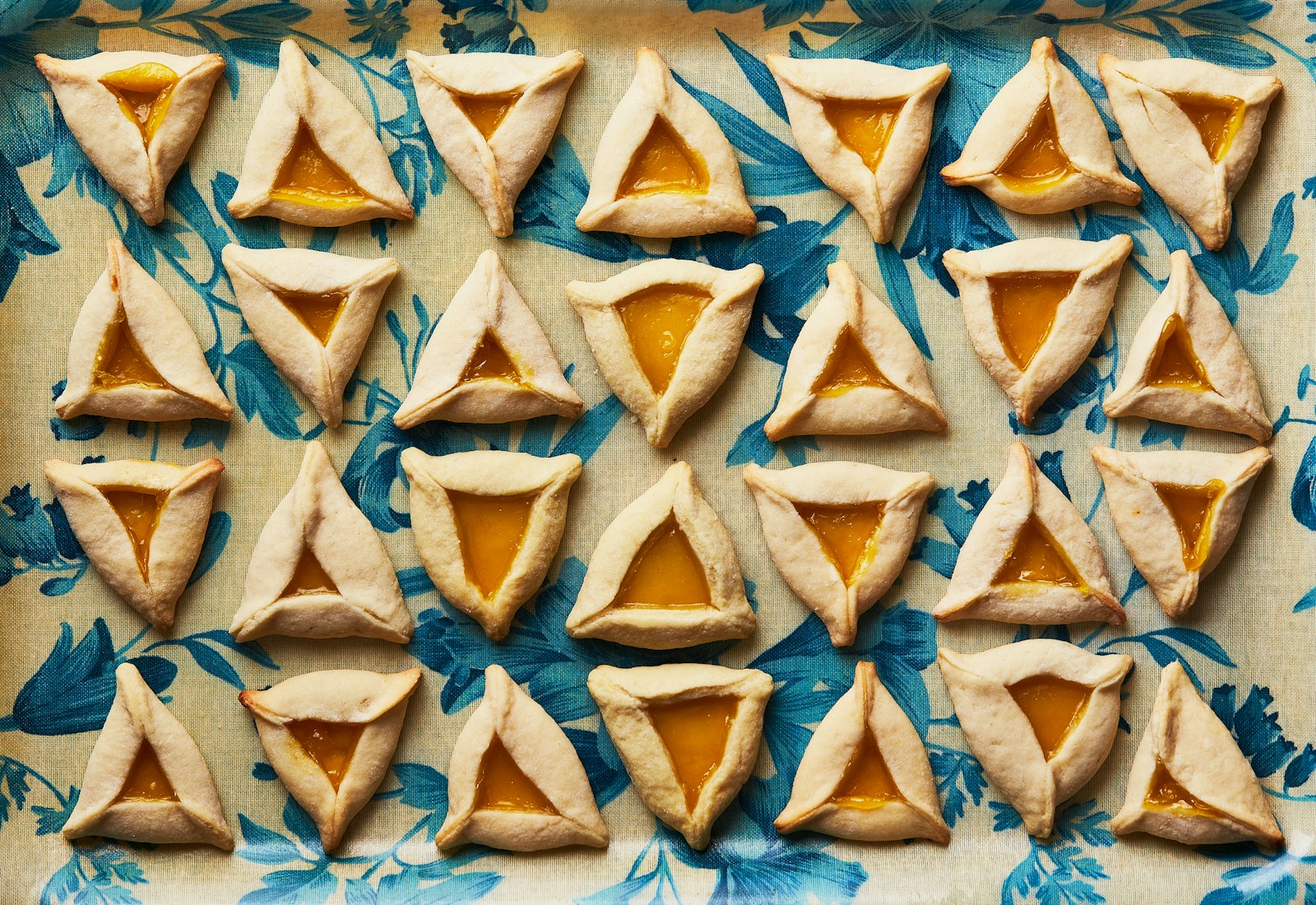 Lemon curd-filled hamantaschens on blue floral dish.