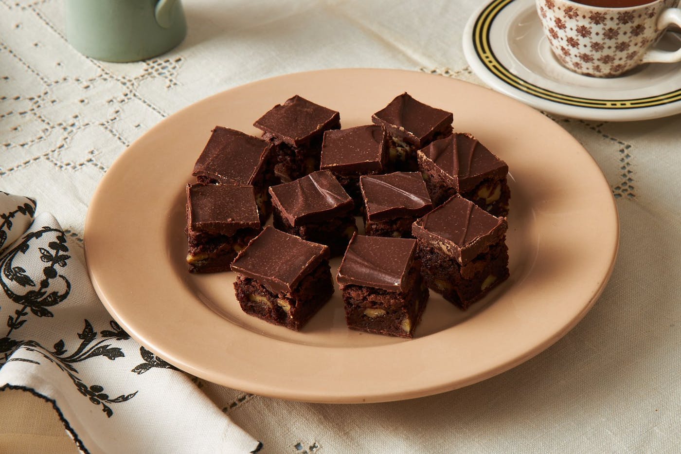 Brownies with coffee, serving plate and patterned napkin. 