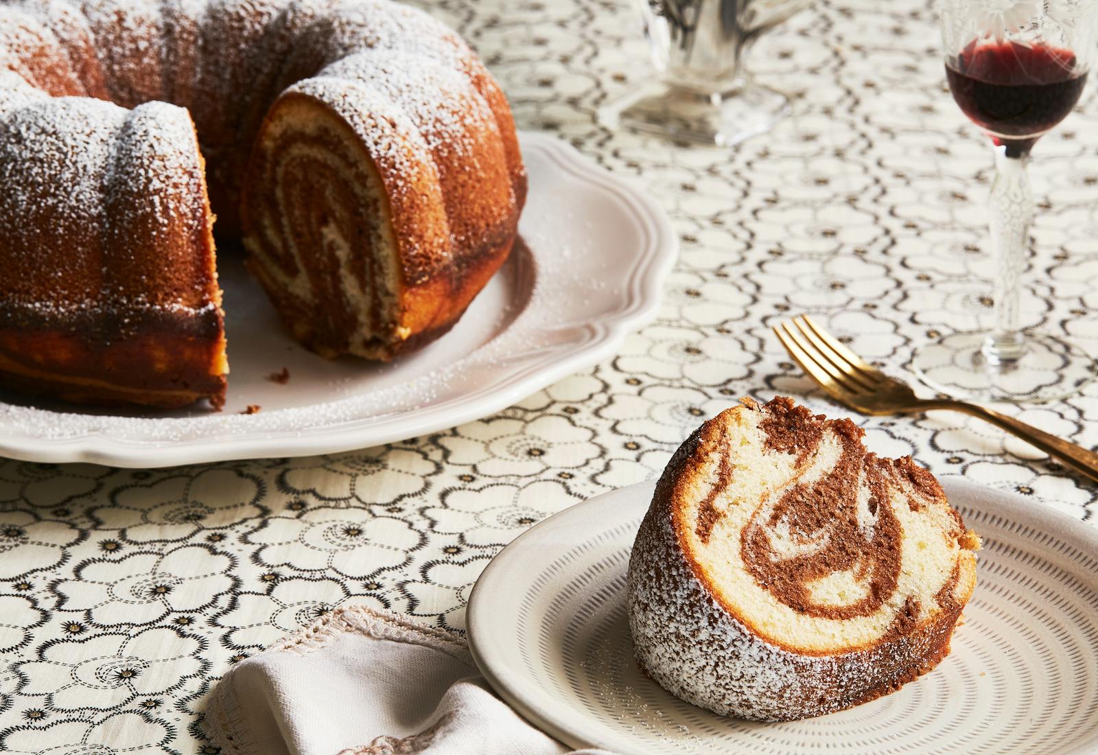 Marble bundt cake on white plate atop white tablecloth.