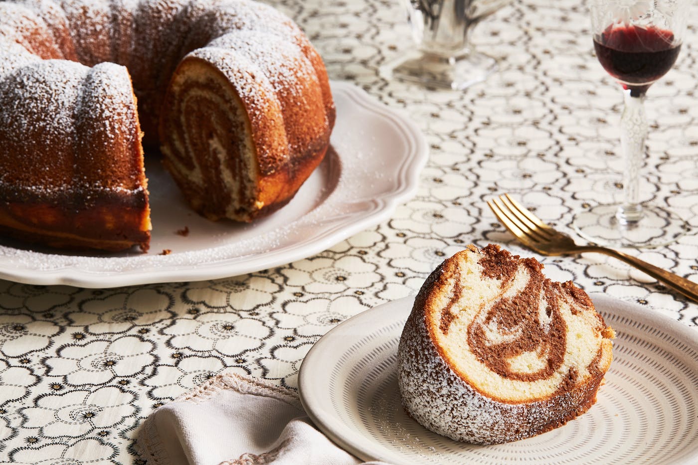 Marble bundt cake on white plate atop white tablecloth.
