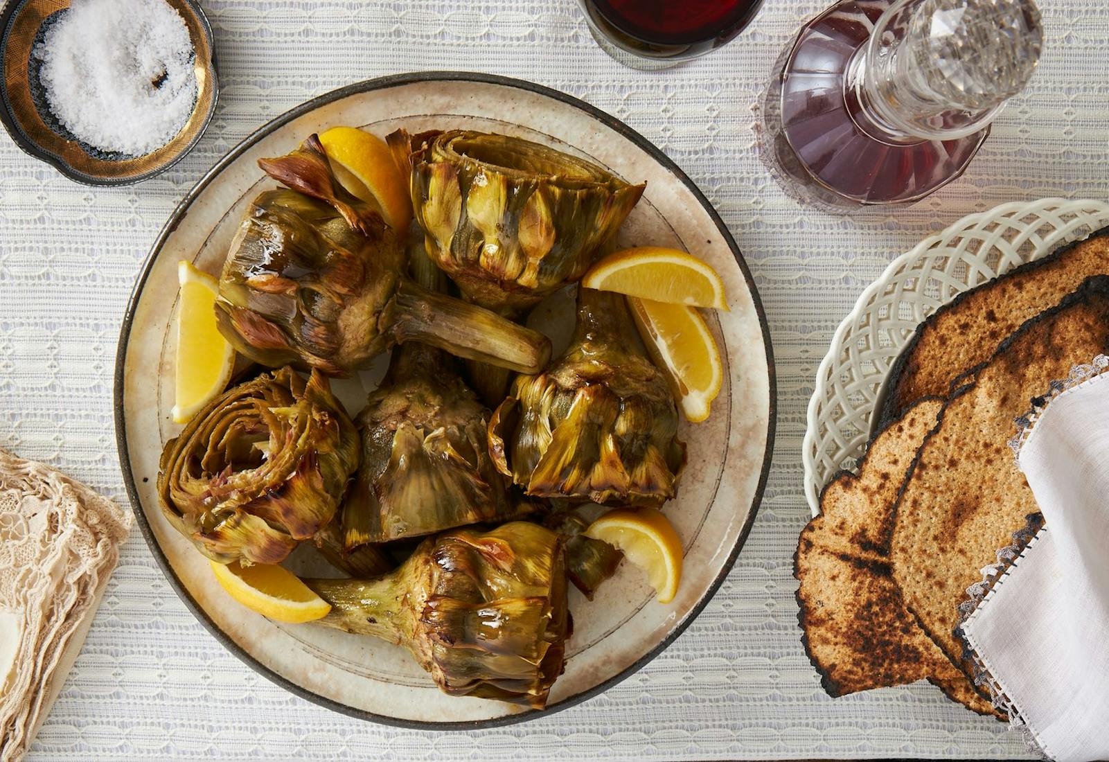 Arichokes with lemon wedges, round matzo and red wine.
