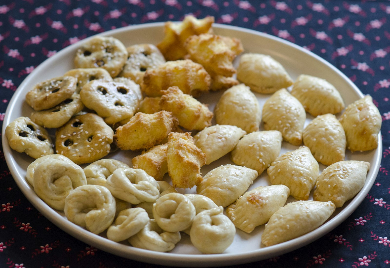 Spread of Iraqi Purim treats: hadgi coconut, cheese sambusak, k'aakat, be'be tamer (clockwise from top center of bowl).