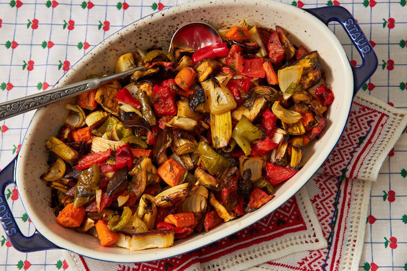 Guvetch in large dutch oven atop festive napkin and fruit-patterned tablecloth.