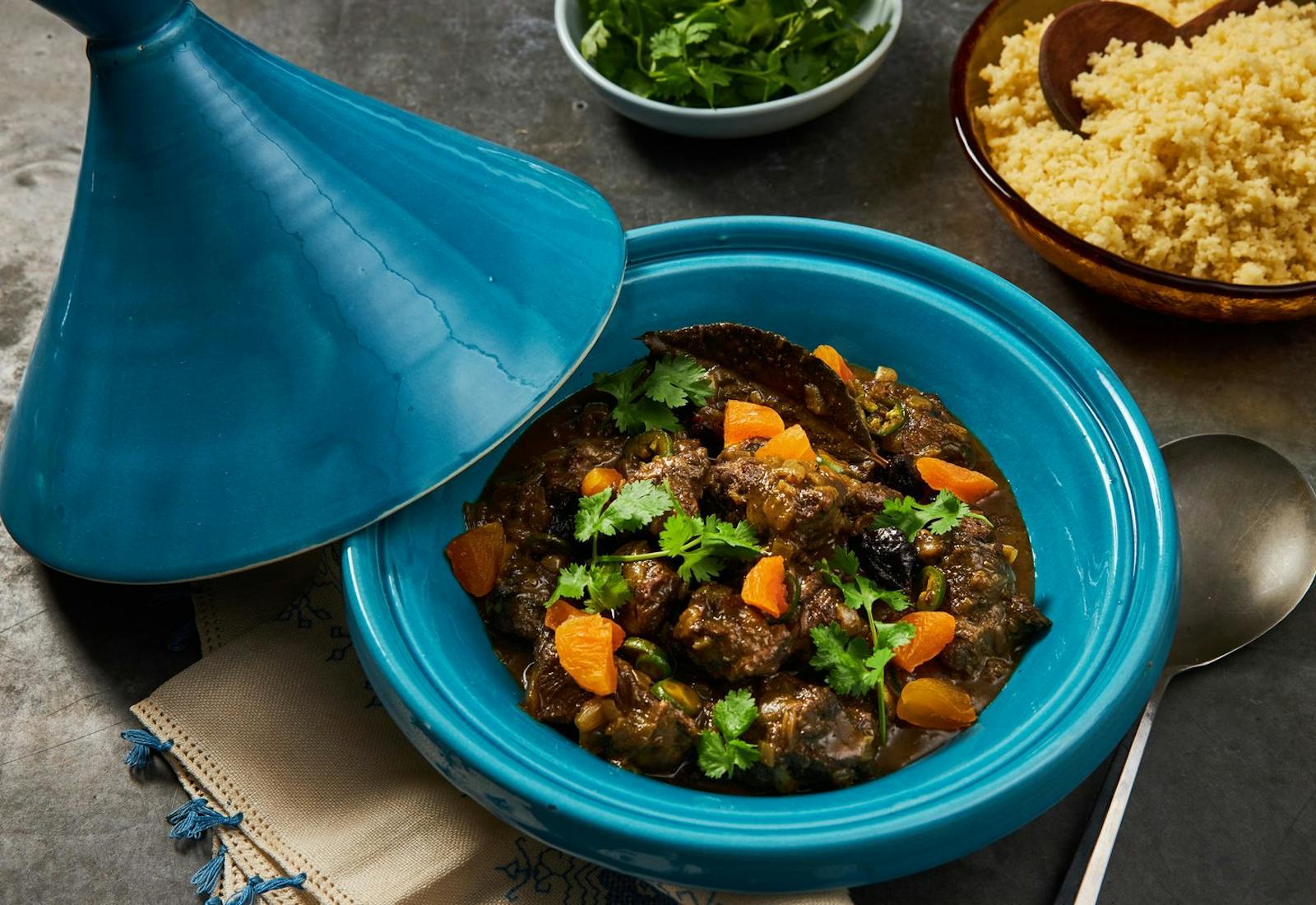 Beef cheek with cilantro in a blue tagine pot, side of couscous.