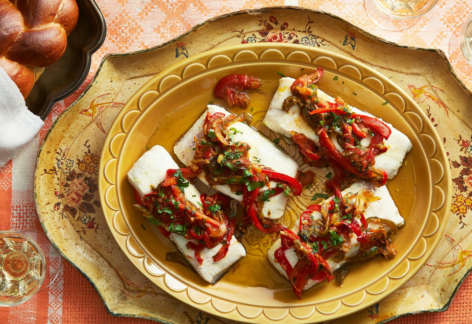 Moroccan fish with vegetables and herbs alongside braided challah.
