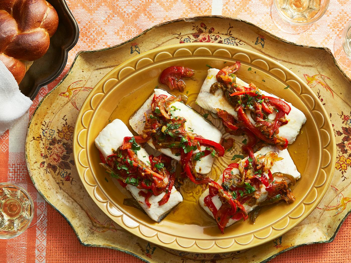 Moroccan fish with vegetables and herbs alongside braided challah.