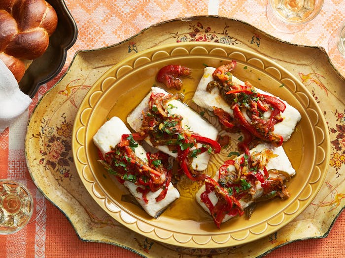 Moroccan fish with vegetables and herbs alongside braided challah.