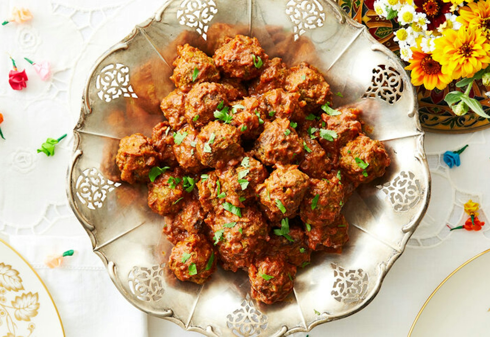 Curry in serving bowl with cilantro, fresh flowers, colorful paper roses.