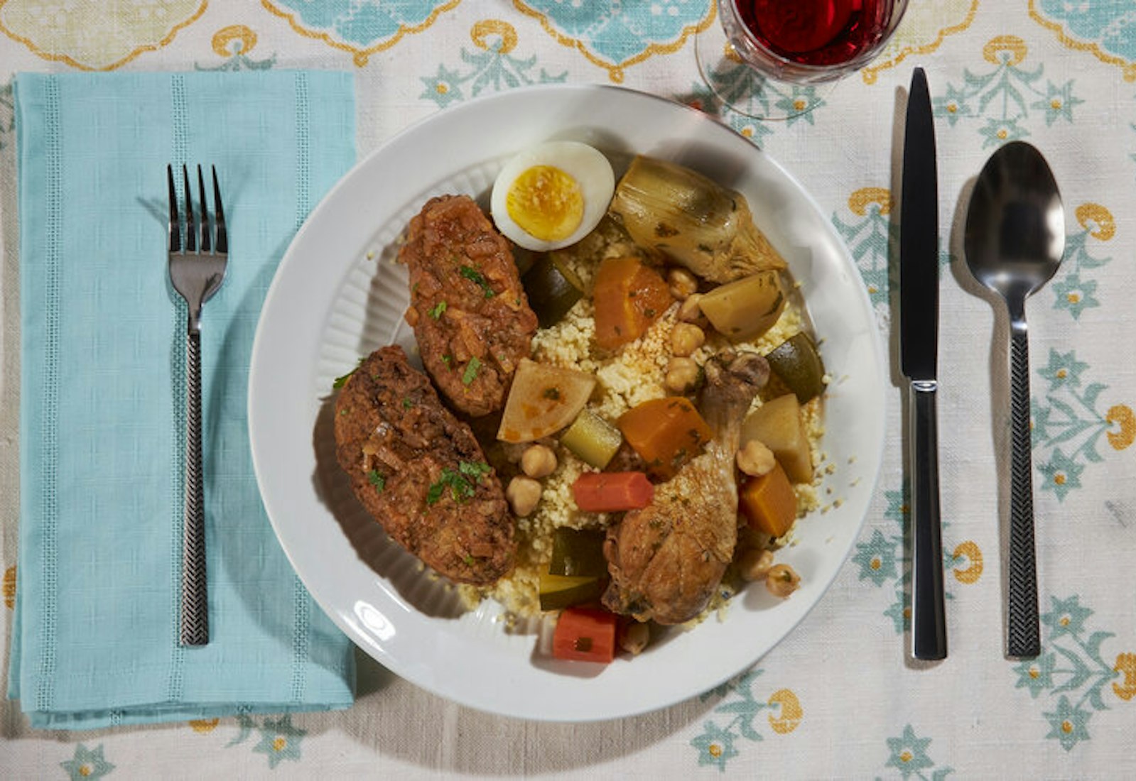 Table setting with chicken patties, couscous and vegetable soup with red wine.