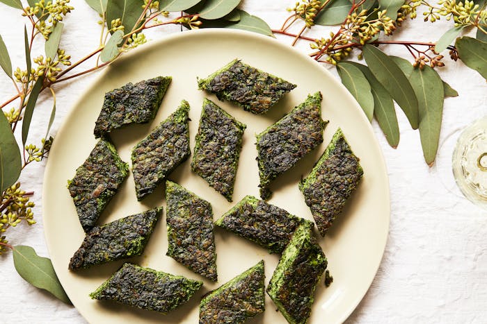 Diamonds of kuku sabzi alongside glass of white wine.