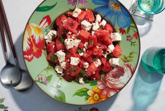 Watermelon and Bulgarian salad with Aleppo and mint on floral bowl atop white surface.