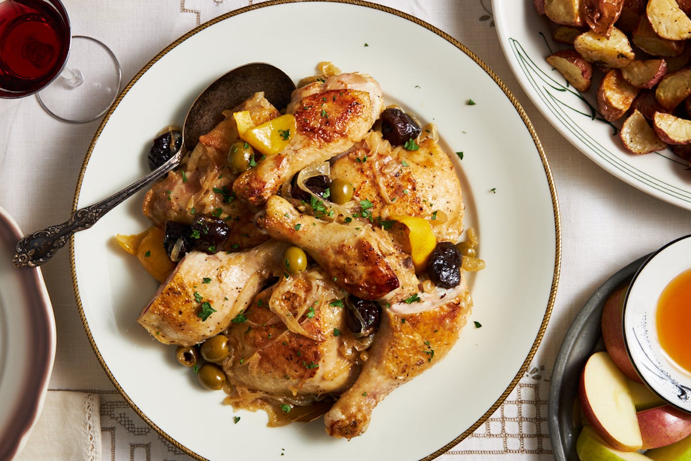 Chicken braised with prunes, olives, and lemon on white plate with serving spoon