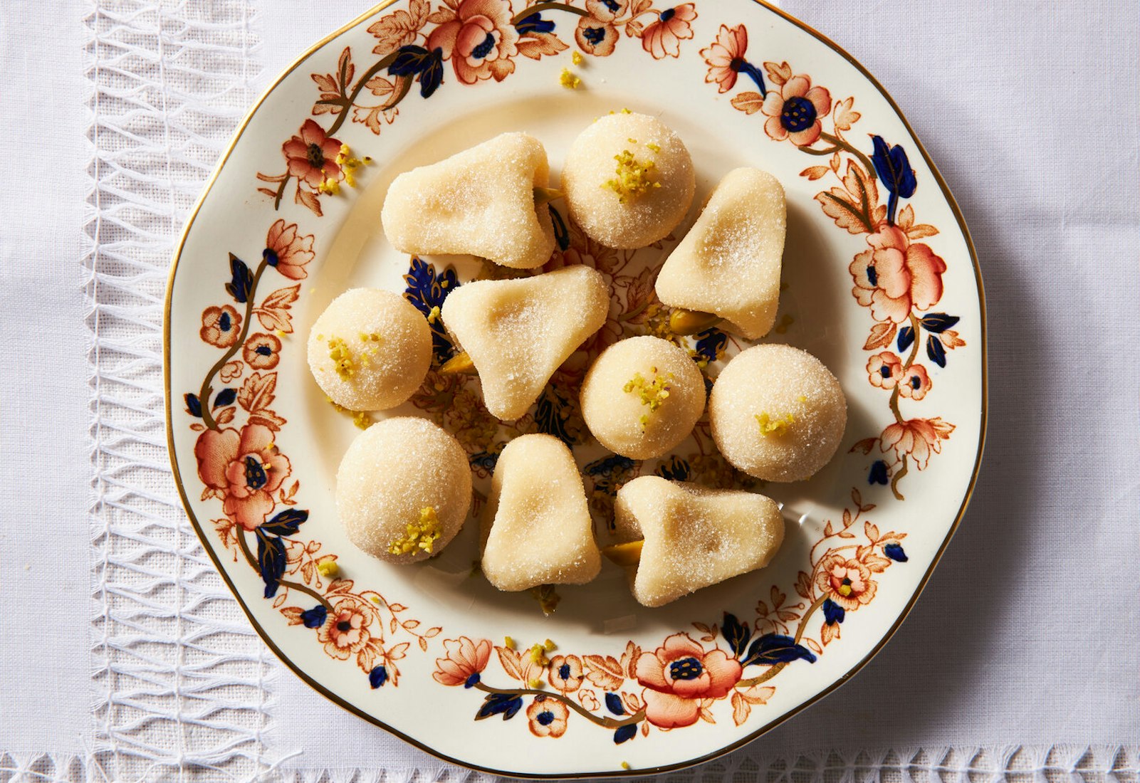 Toot sprinkled with chopped pistachio on red and black floral dish.
