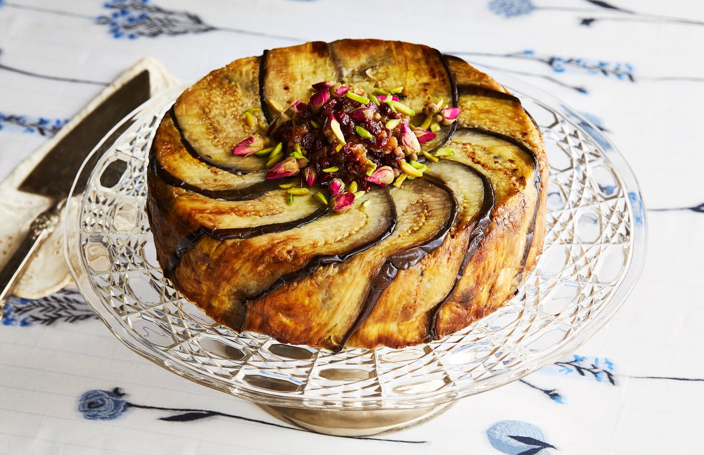 Tachin with barberries, pistachios and rose buds atop glass serving tray.