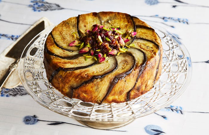 Tachin with barberries, pistachios and rose buds atop glass serving tray.